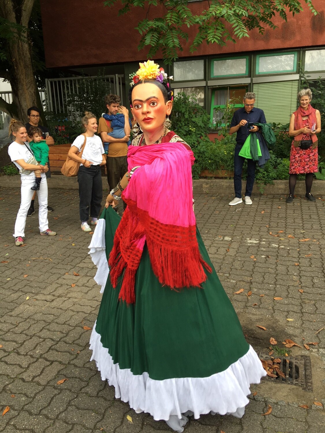 Eine Person mit einer Maske und bunter Kleidung führt etwas vor.