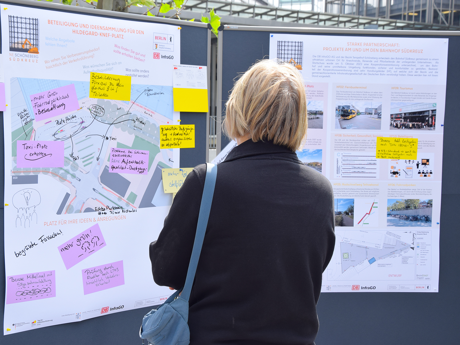 Eine Frau schaut sich zwei Infotafeln an.