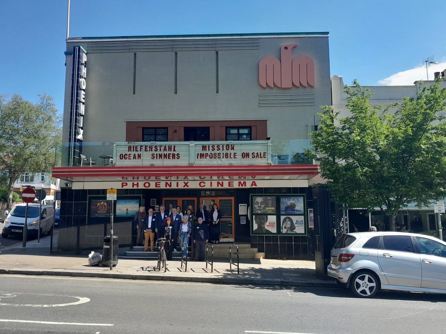 Eine Gruppe Menschen vor einem Gebäude, auf dem Phoenix Cinema steht.