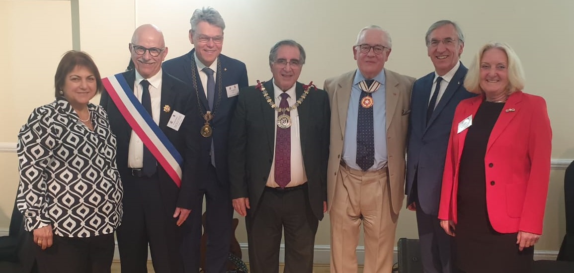 Sieben Personen stehen nebeneinander und lächeln.