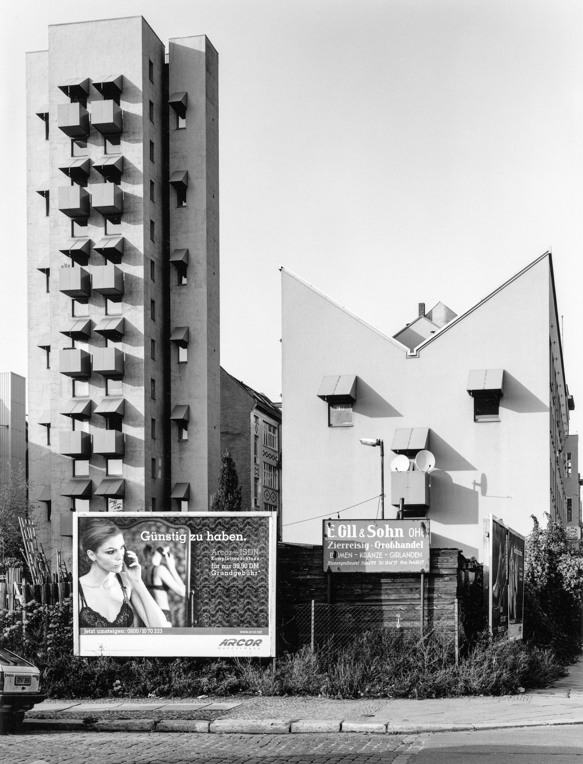 Schwarzweißfotografie von Gebäuden und eine Werbeschild an einer Straße.