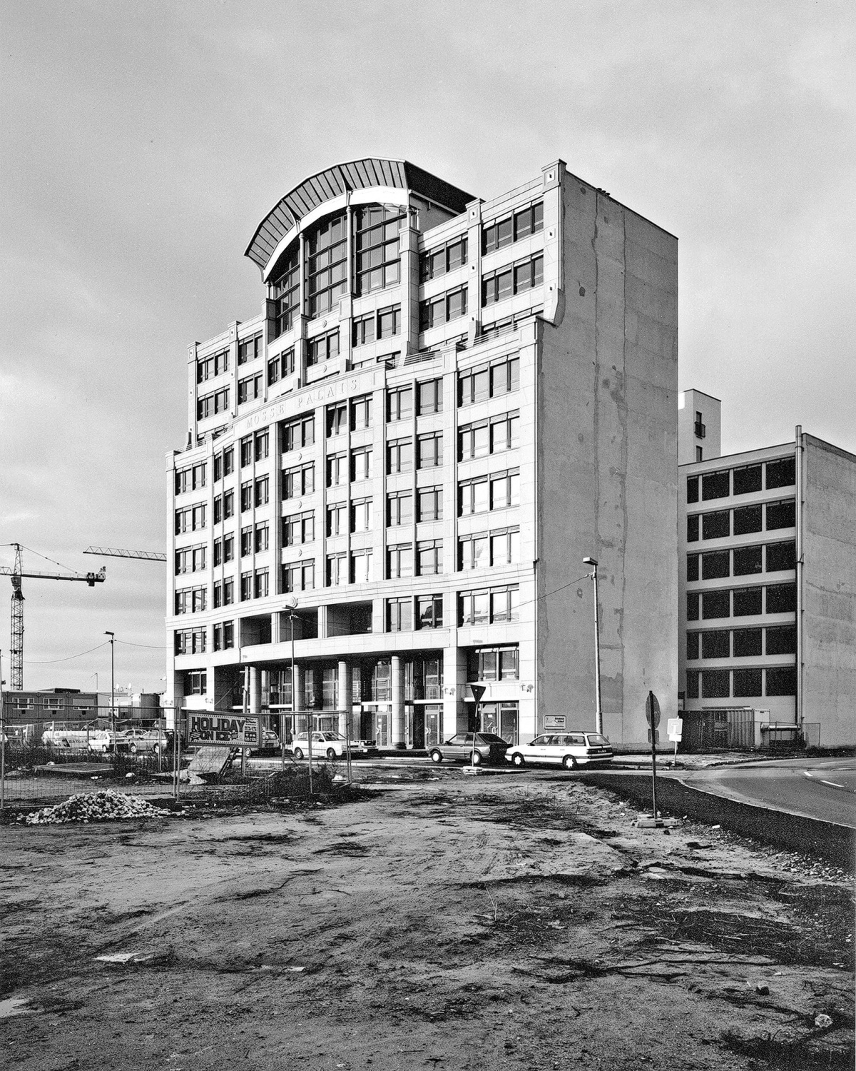 Schwarzweißfotografie von einen großen Gebäude hinter einer freien Baufläche.