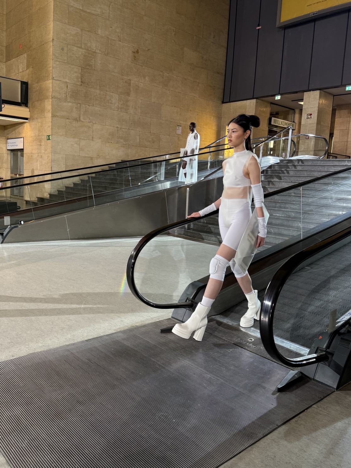 Zwei Models laufen Rollbahnen in eine Halle herunter.