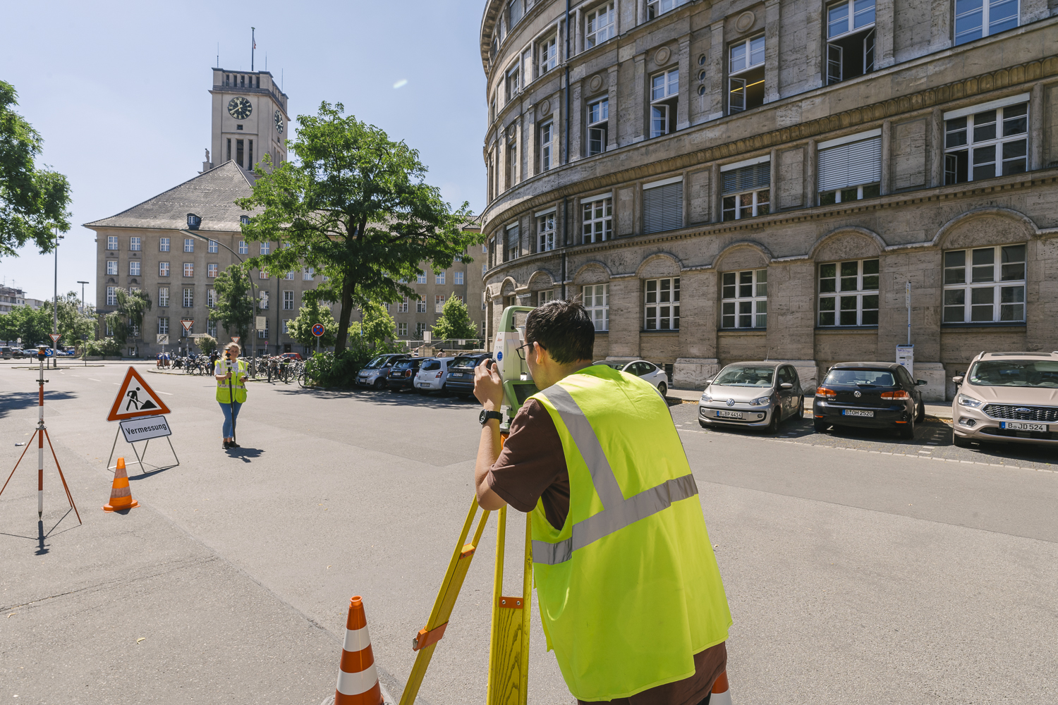 Zwei Personen in Warnwesten stehen mit Messgeräten auf einer Straße.