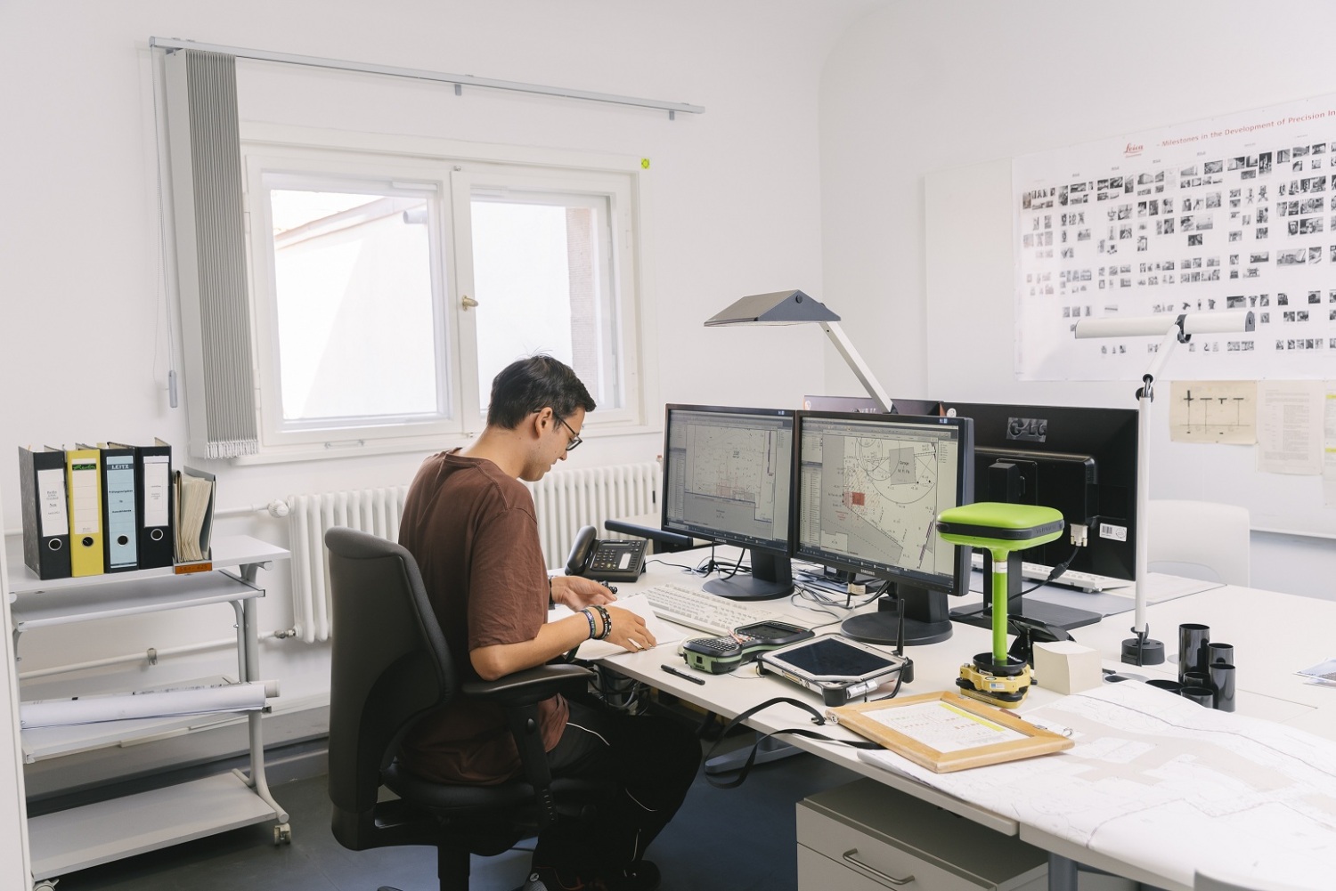 Ein Mann sitzt an einem Schreibtisch mit einem PC und zwei Monitoren.