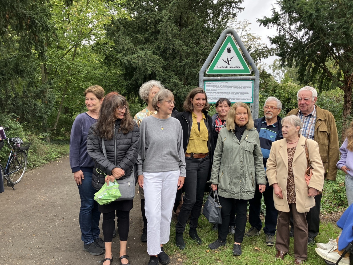 Eine Gruppe Menschen steht zusammen vor einem Grünflächen-Schild.