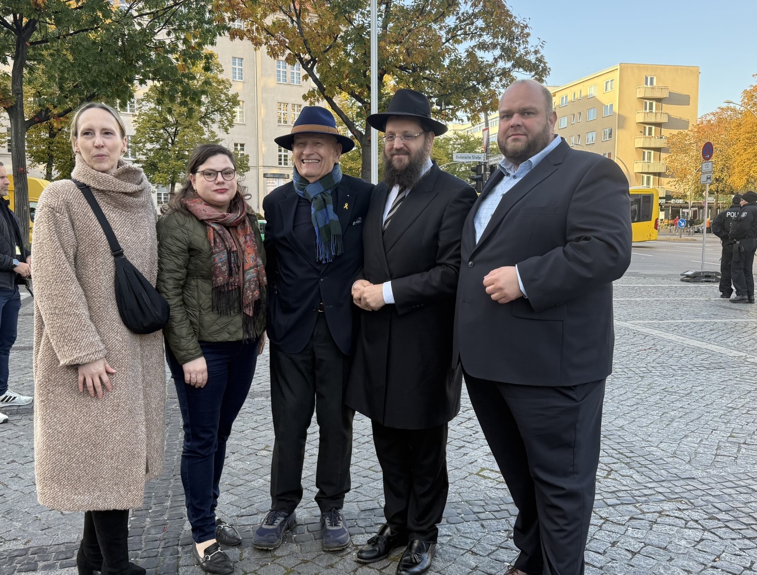 Fünf Personen stehen nebeneinander auf einem Platz.