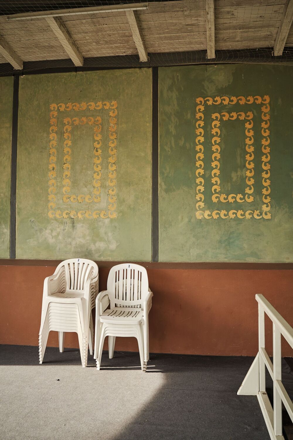 Plastikstühle sind vor einer Wand übereinander gestapelt.