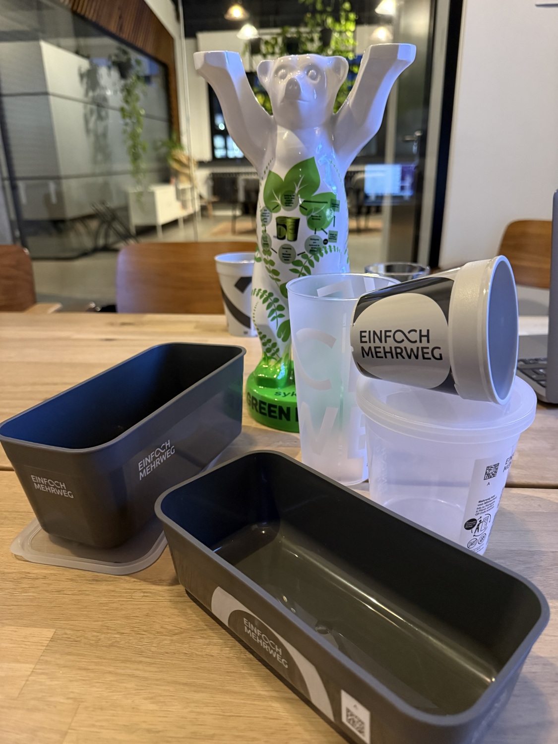 Green Buddy Award und verschiedene Mehrwegverpackungen auf einem Tisch