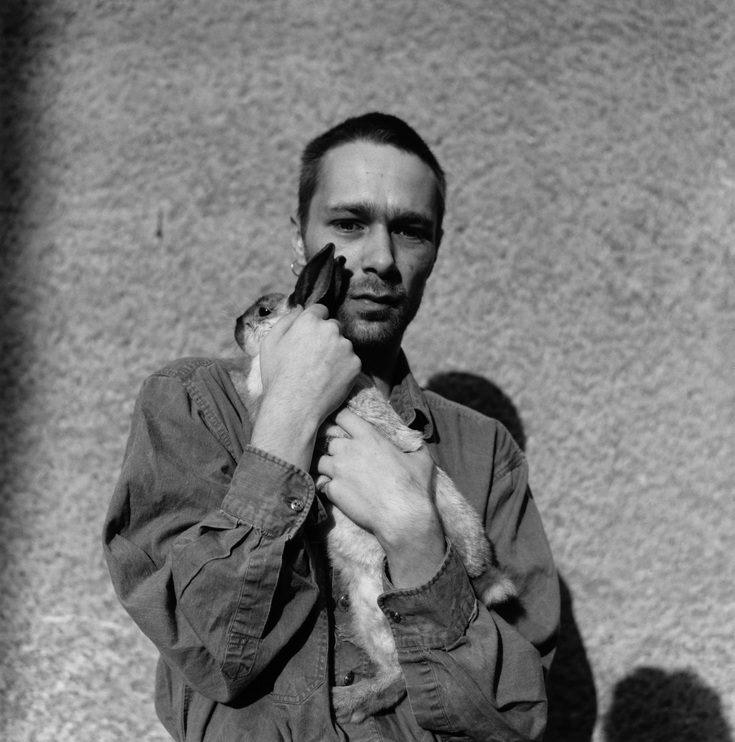 Schwarzweißfotografie; ein Mann hält einen Hasen.