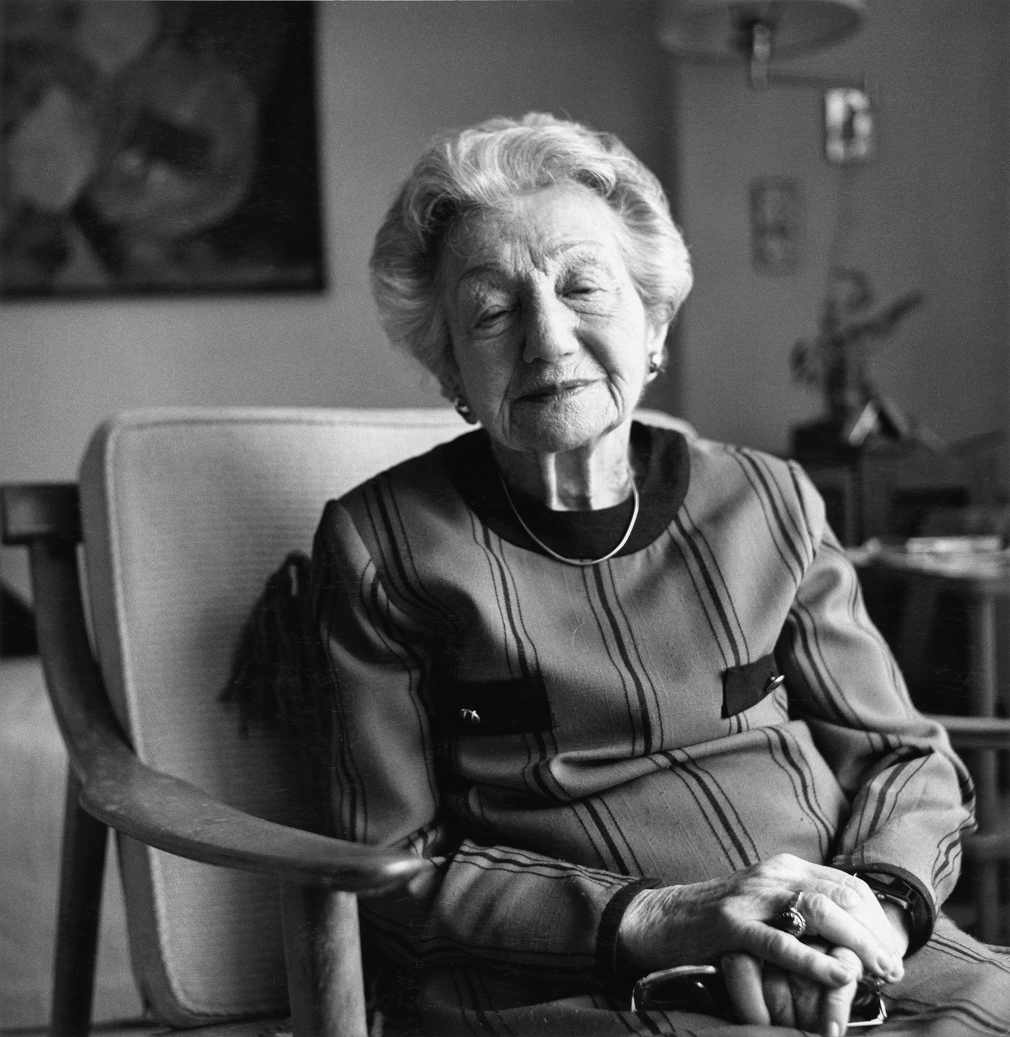 Schwarzweißfotografie; eine ältere Frau sitzt in einem Stuhl.