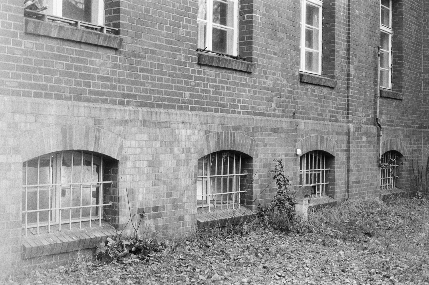 ein schwarz-weiß Foto von einer Hauswand mit vergitterten Fenstern