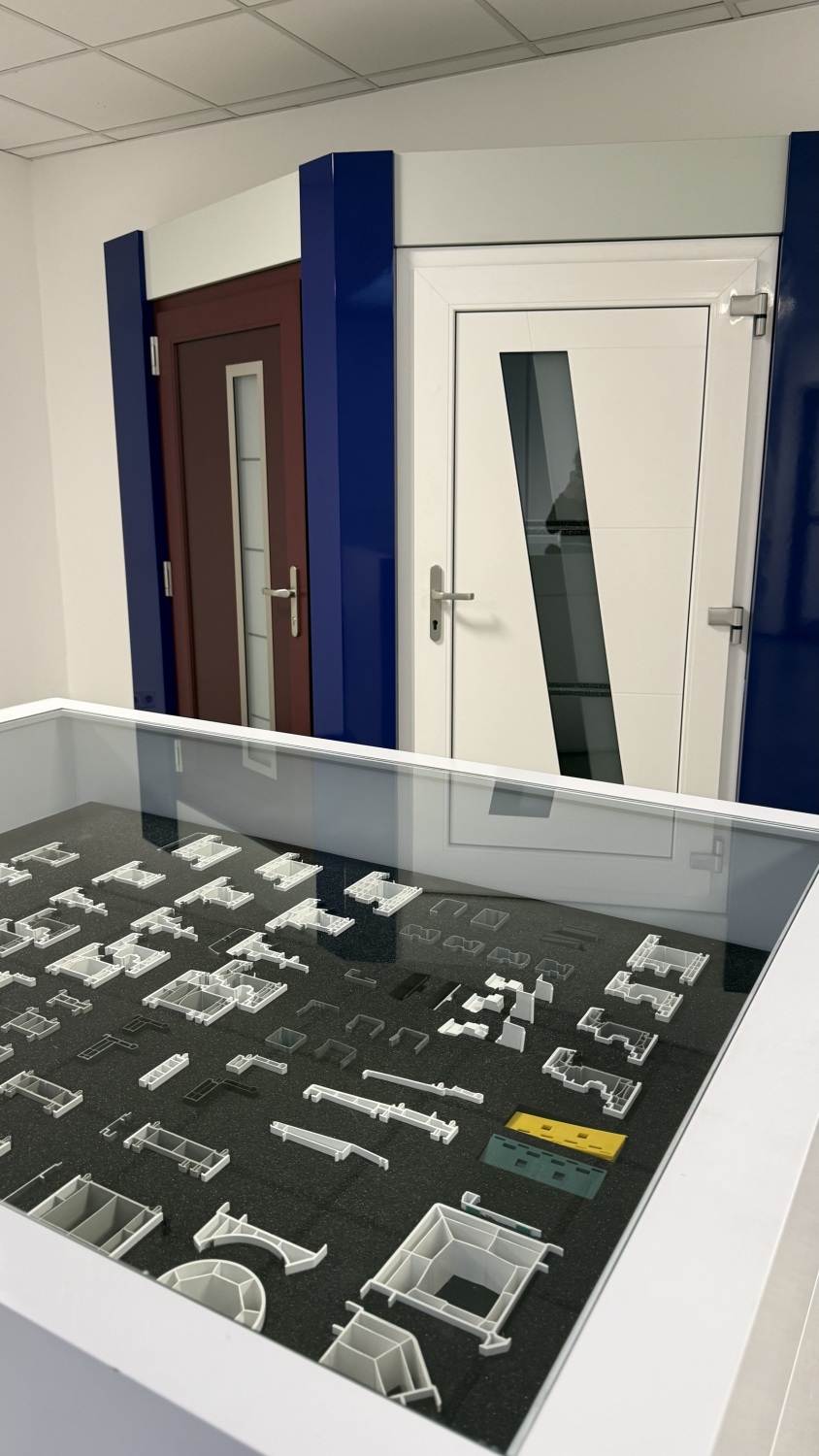 Zwei Mustertüren an einer Wand und mehrere Bauteile in einer Vitrine