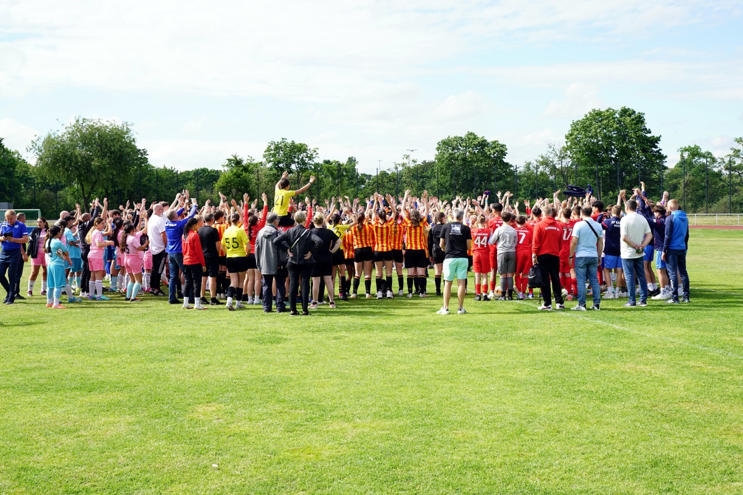 Eine Gruppe Menschen, zum größten Teil Jugendliche, auf einem Fußballfeld.
