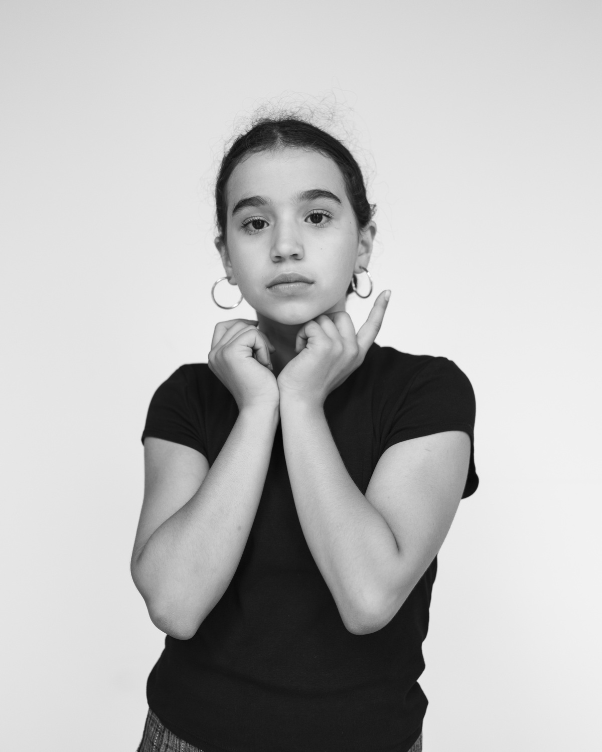 Schwarzweißfotografie einer jungen Frau bzw. Mädchens, das ihre Hände unter dem Gesicht hält