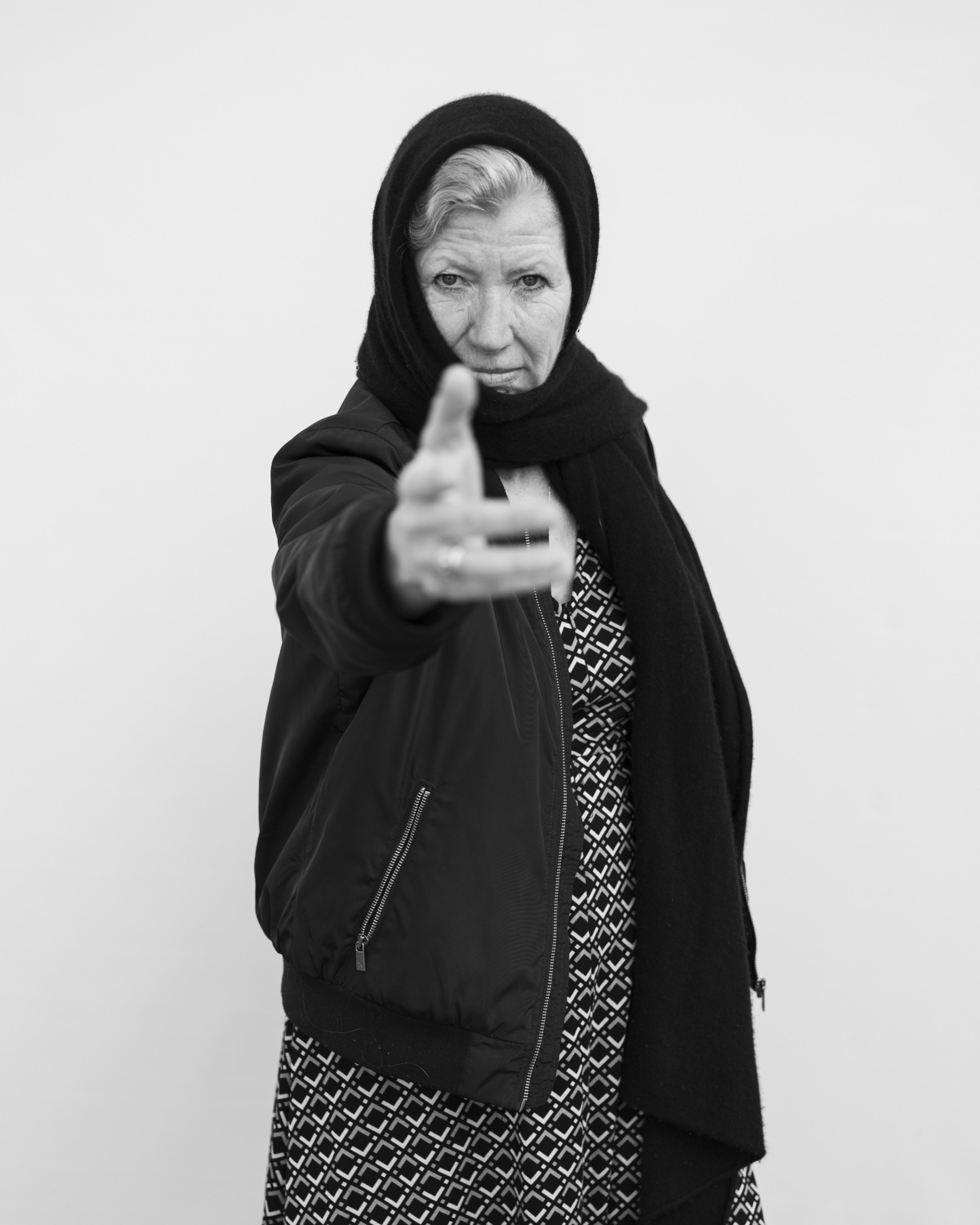 Schwarzweißfotografie einer Frau mit Kopftuch, die uns eine Hand entgegenstreckt