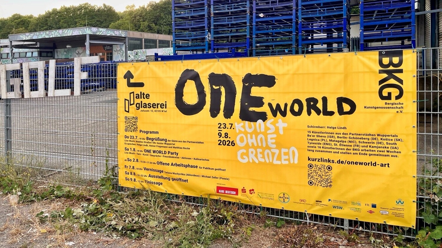 Großes gelbes Werbebanner für das ONE WORLD Kunstevent mit Infos zu den Veranstaltungen