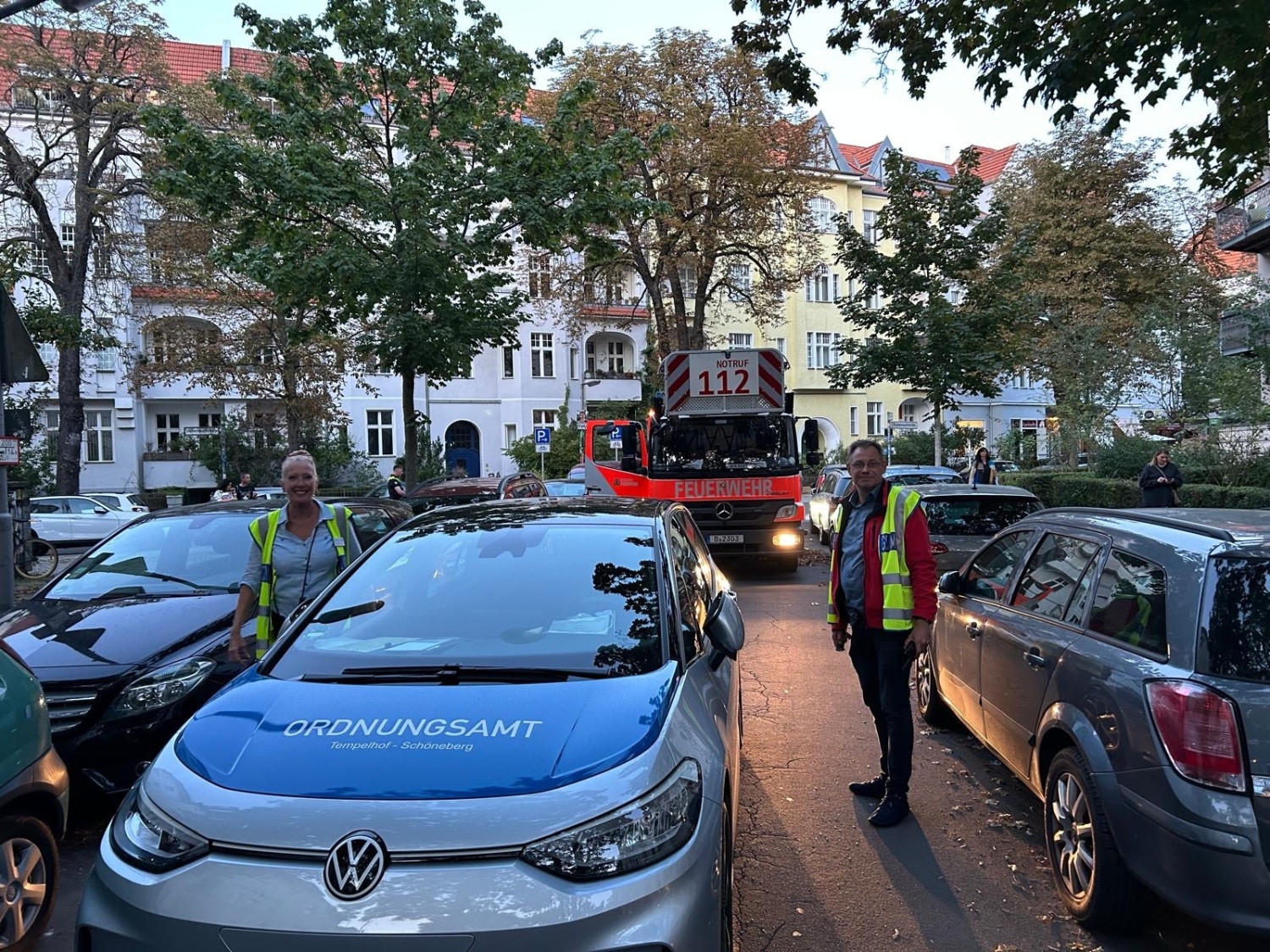 zwei Menschen in Warnwesten neben einem Wagen des Ordnungsamtes Tempelhof-Schöneberg