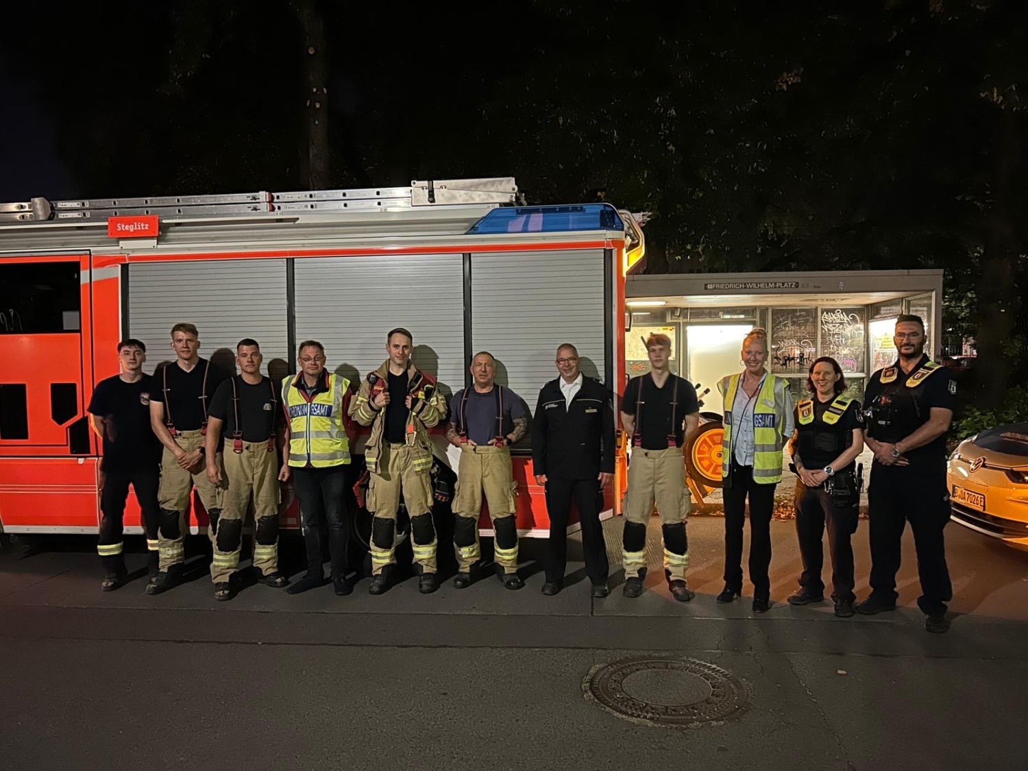 eine Gruppe Menschen in Arbeitskleidung vor einem Feuerwehrwagen