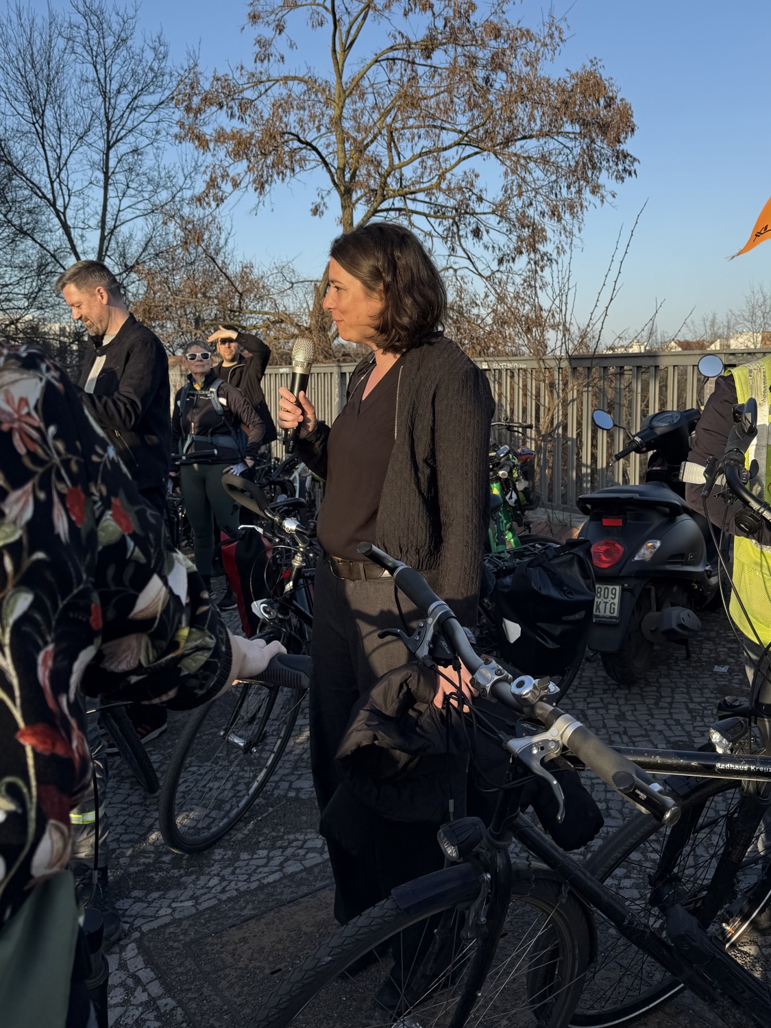 Eine Frau mit einem Mikrofon in der Hand steht neben Fahrrädern in der Monumentenstraße