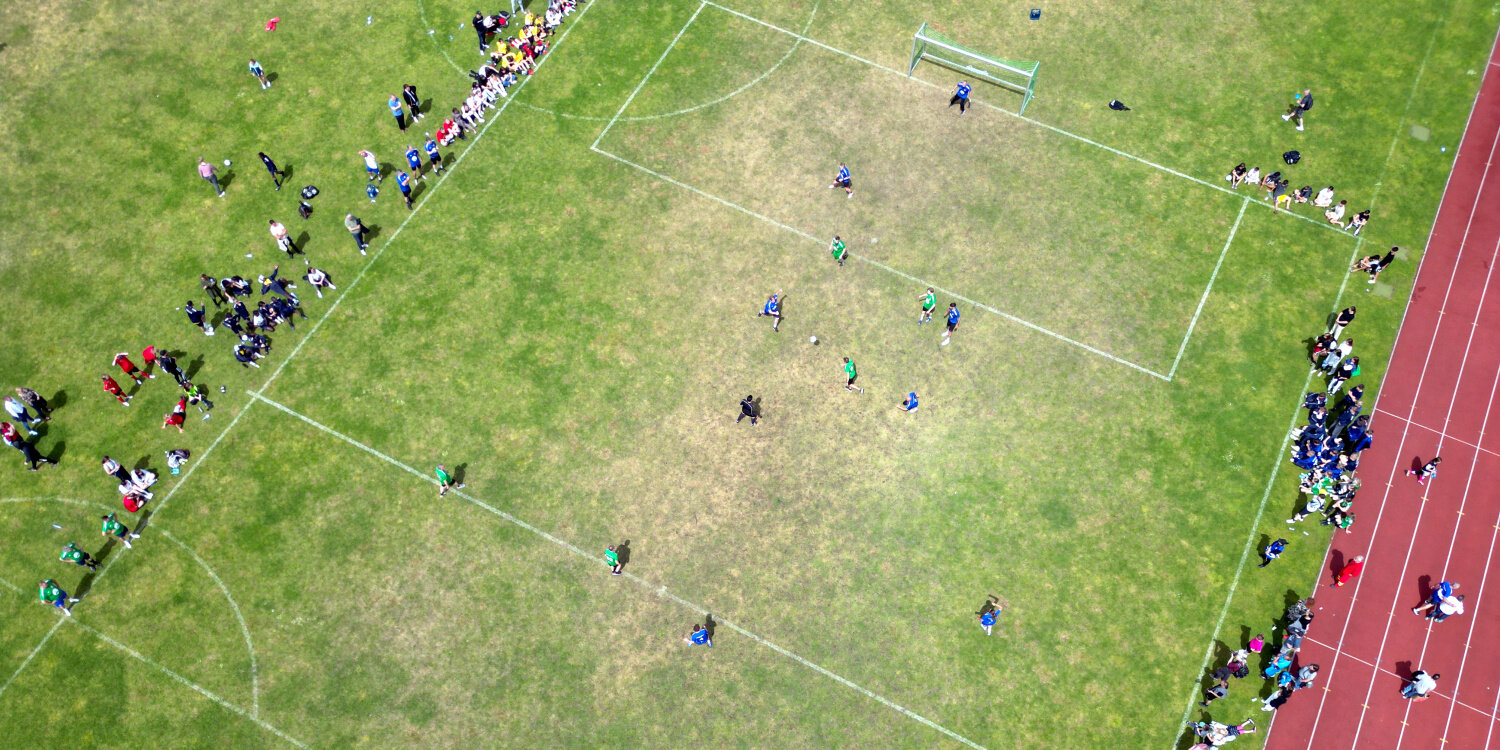Eine Luftaufnahme von einem Fußballplatz auf welchem ein Spiel stattfindet.