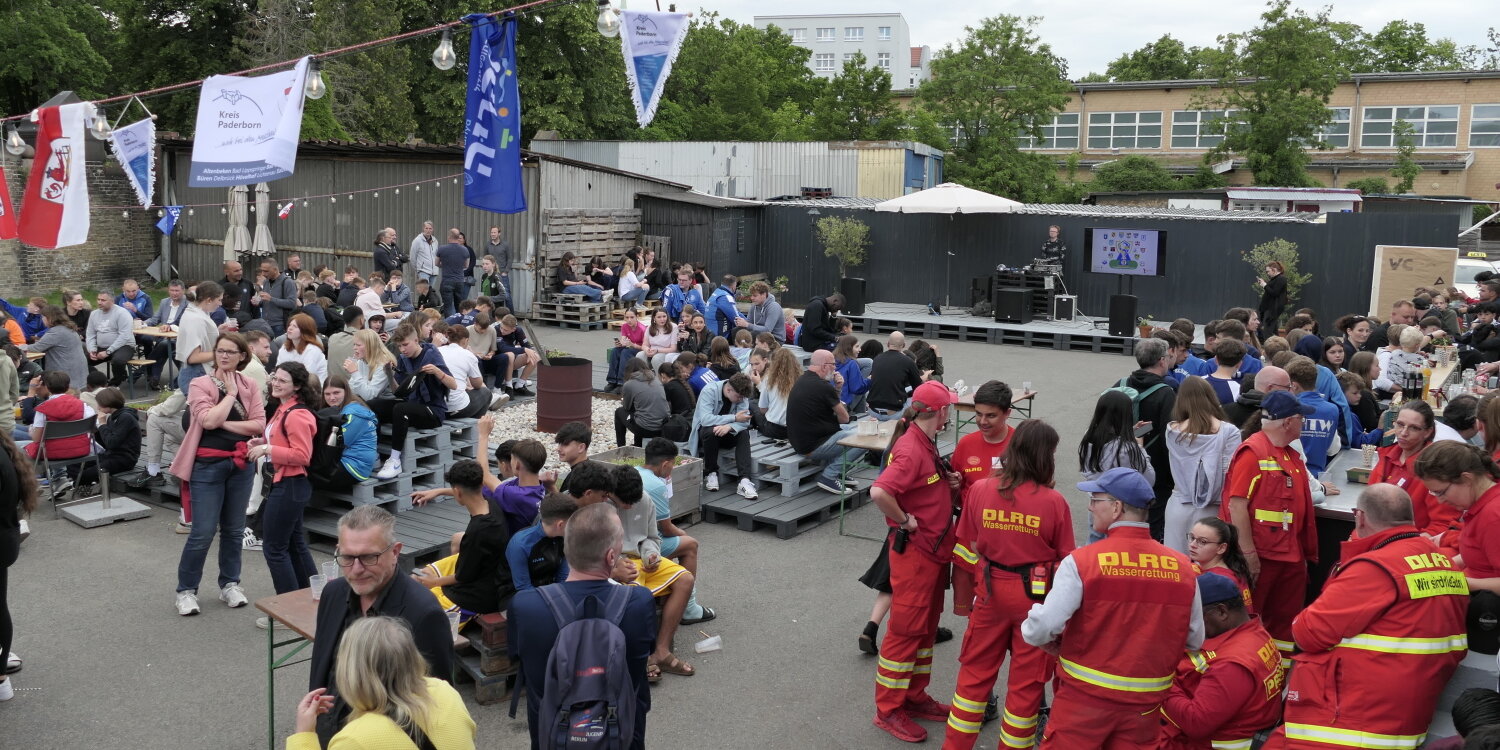 Ein Veranstaltungsgelände auf welchem viele Personen sitzen und umherlaufen.