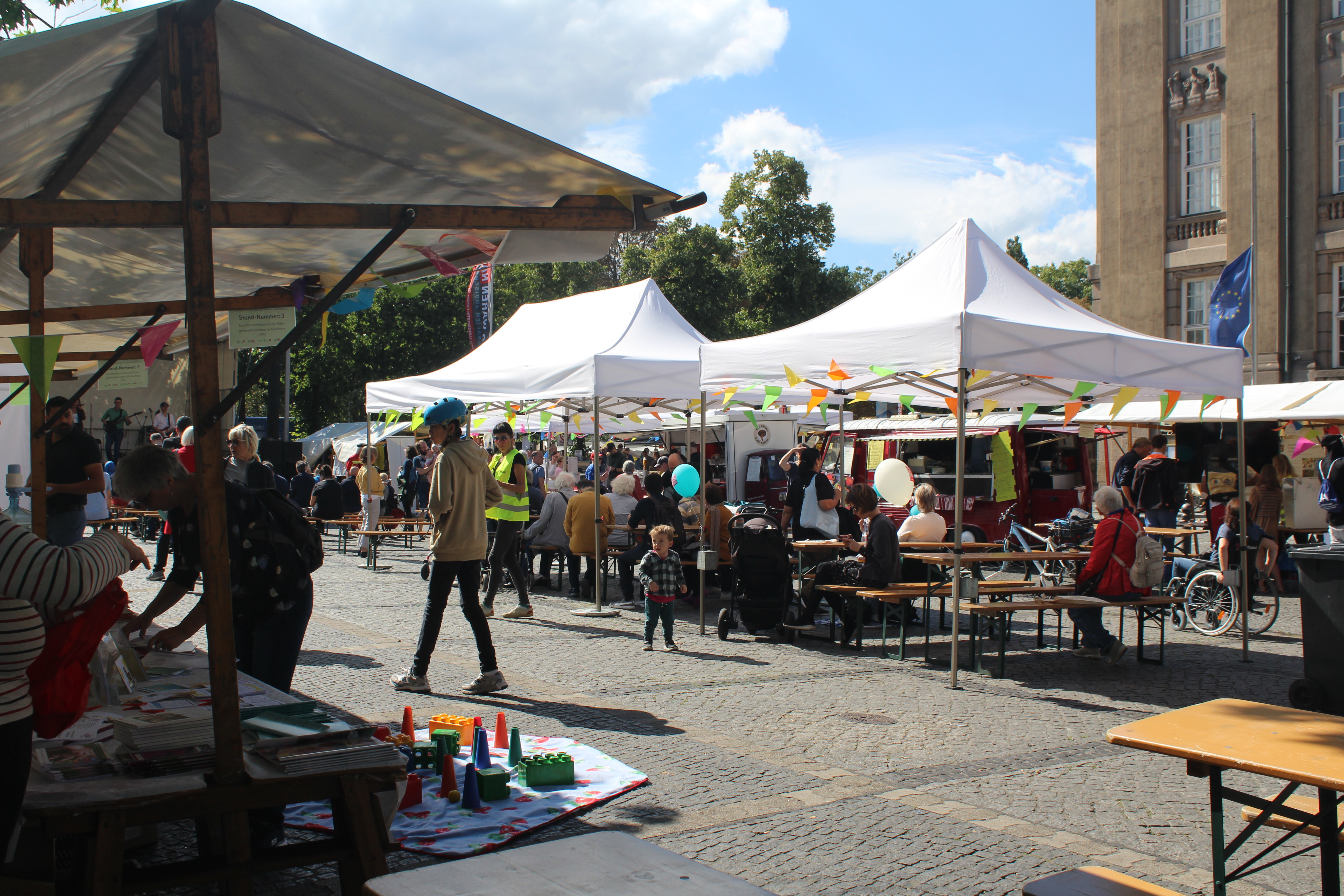 Menschen an Informationsständen und Zelten