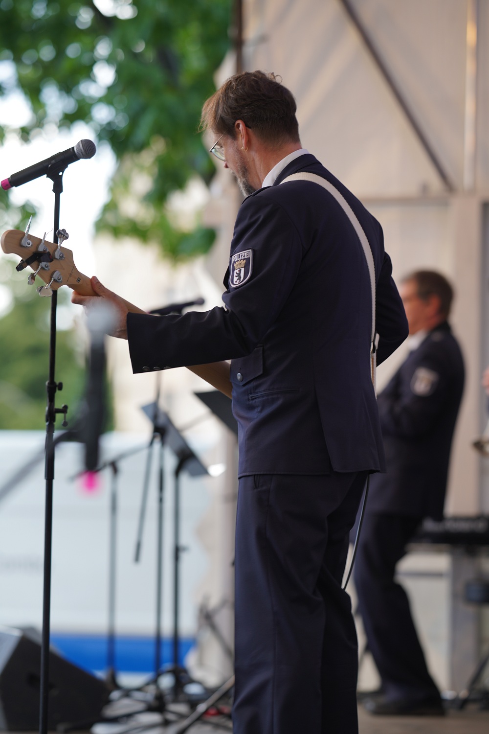 ein Mann in Polizei-Uniform spielt Gitarre auf einer großen Bühne