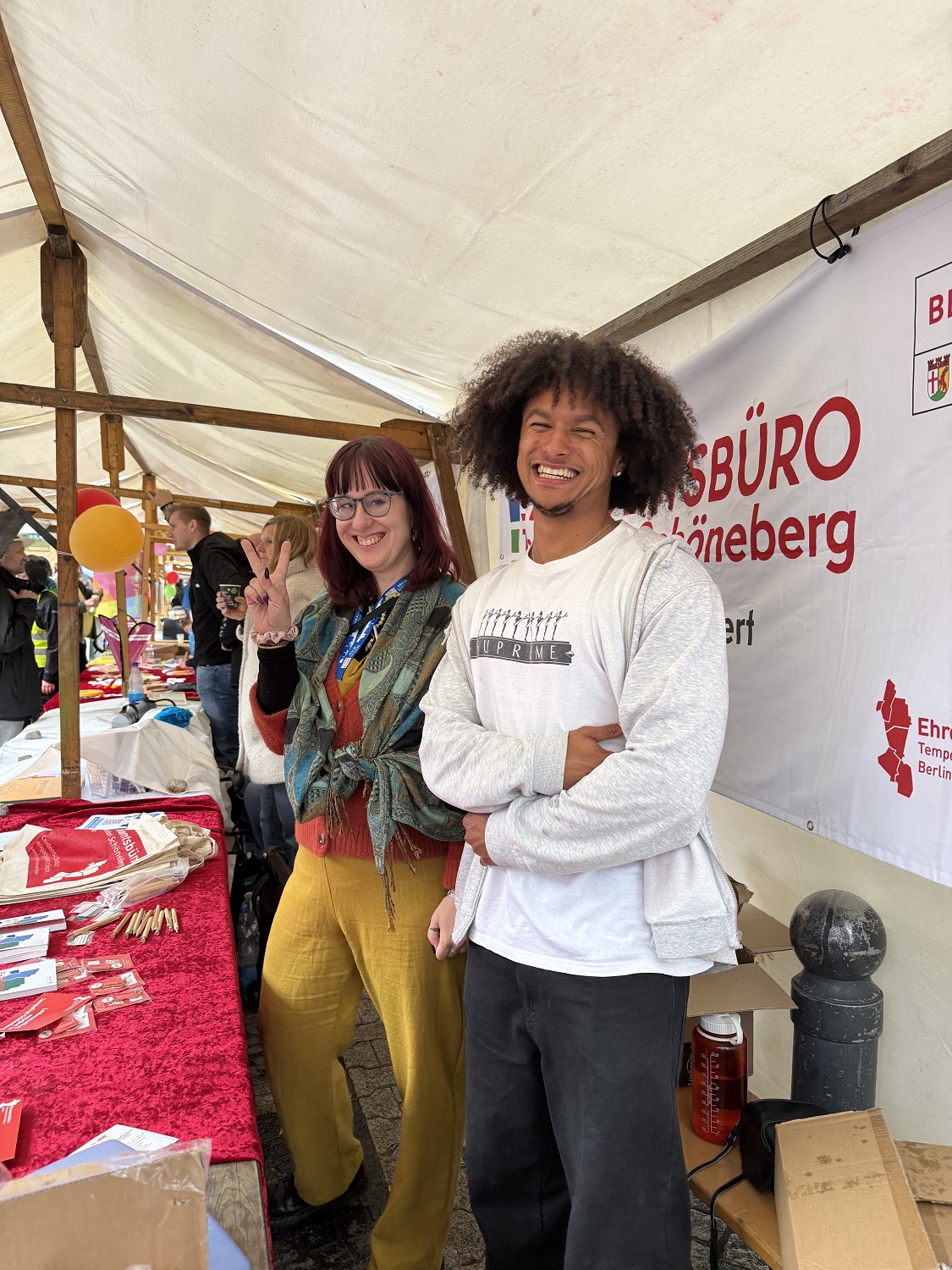 zwei Personen stehen lächelnd an einem Stand