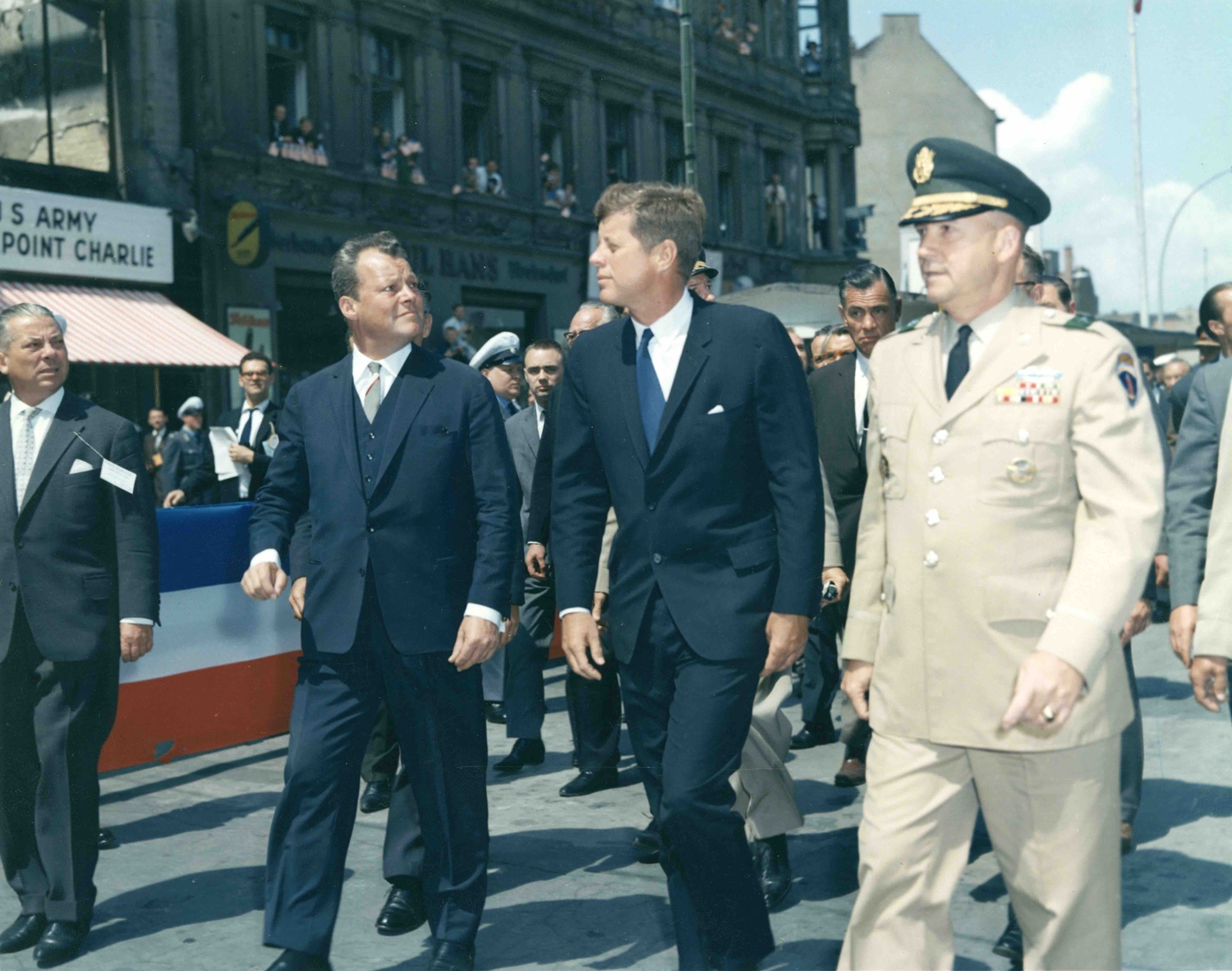 26. Juni 1963 Die ursprüngliche Bildunterschrift auf der Rückseite des Abzugs lautet: „Präsident John F. Kennedy trifft am ‚Checkpoint Charlie‘ in Berlin ein. Begleitet wird der Präsident von Brigadegeneral Frederick O. Hartel, Kommandeur der Berlin-Brigade, und dem West-Berliner Bürgermeister Willy Brandt.“ Berlin, Deutschland