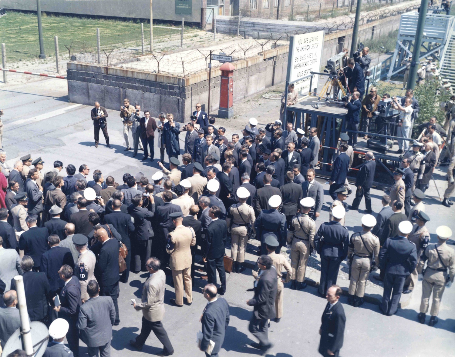 26. Juni 1963 Die ursprüngliche Bildunterschrift auf der Rückseite des Abzugs lautet: „Präsident John F. Kennedy am ‚Checkpoint Charlie‘ mit dem westdeutschen Bundeskanzler Konrad Adenauer, dem West-Berliner Bürgermeister Willy Brandt und Generalmajor James R. Polk, dem US-Kommandeur in Berlin“ Berlin, Deutschland