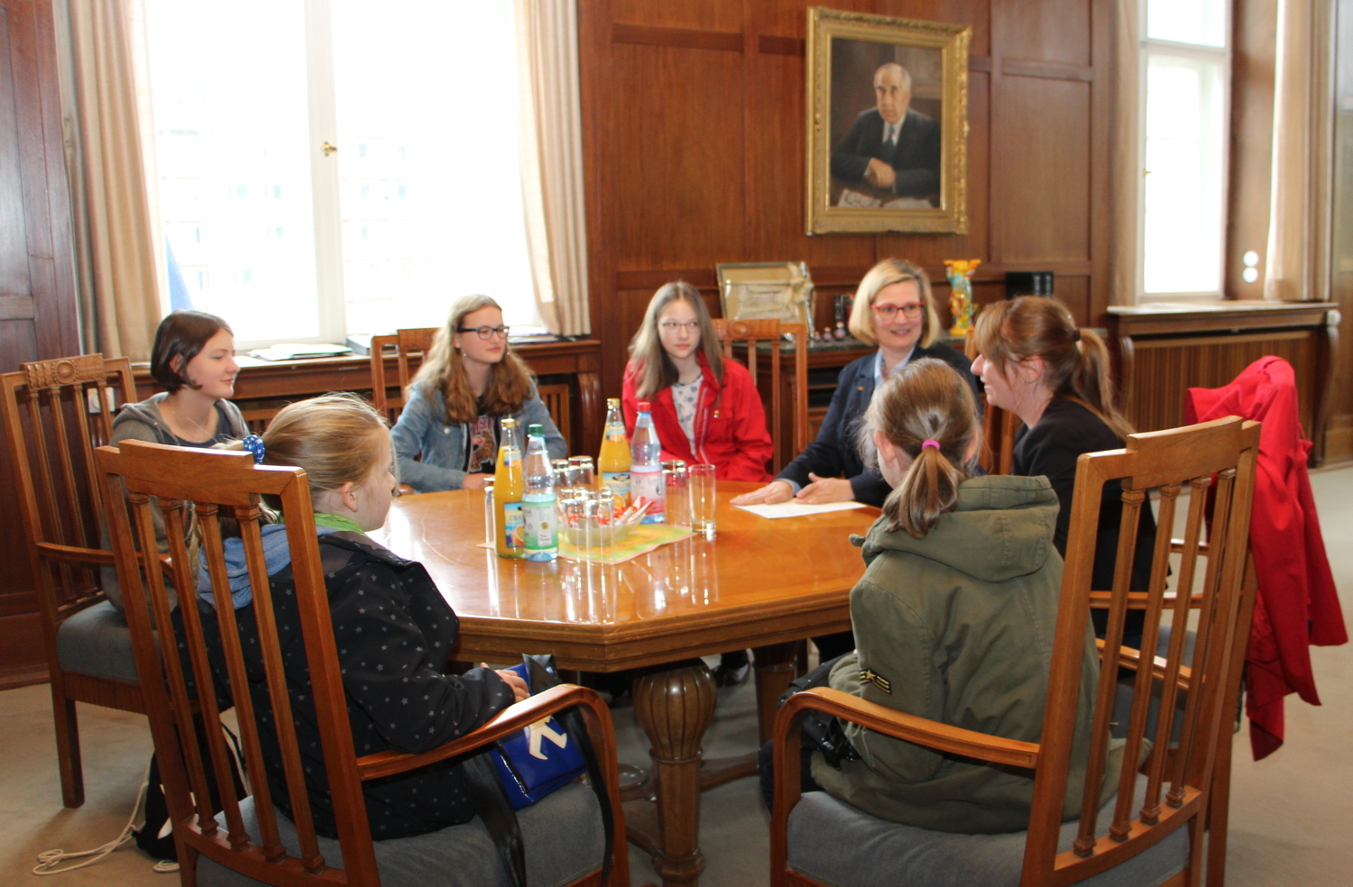 2 Frauen und 5 Mädchen diskutieren am Tisch.