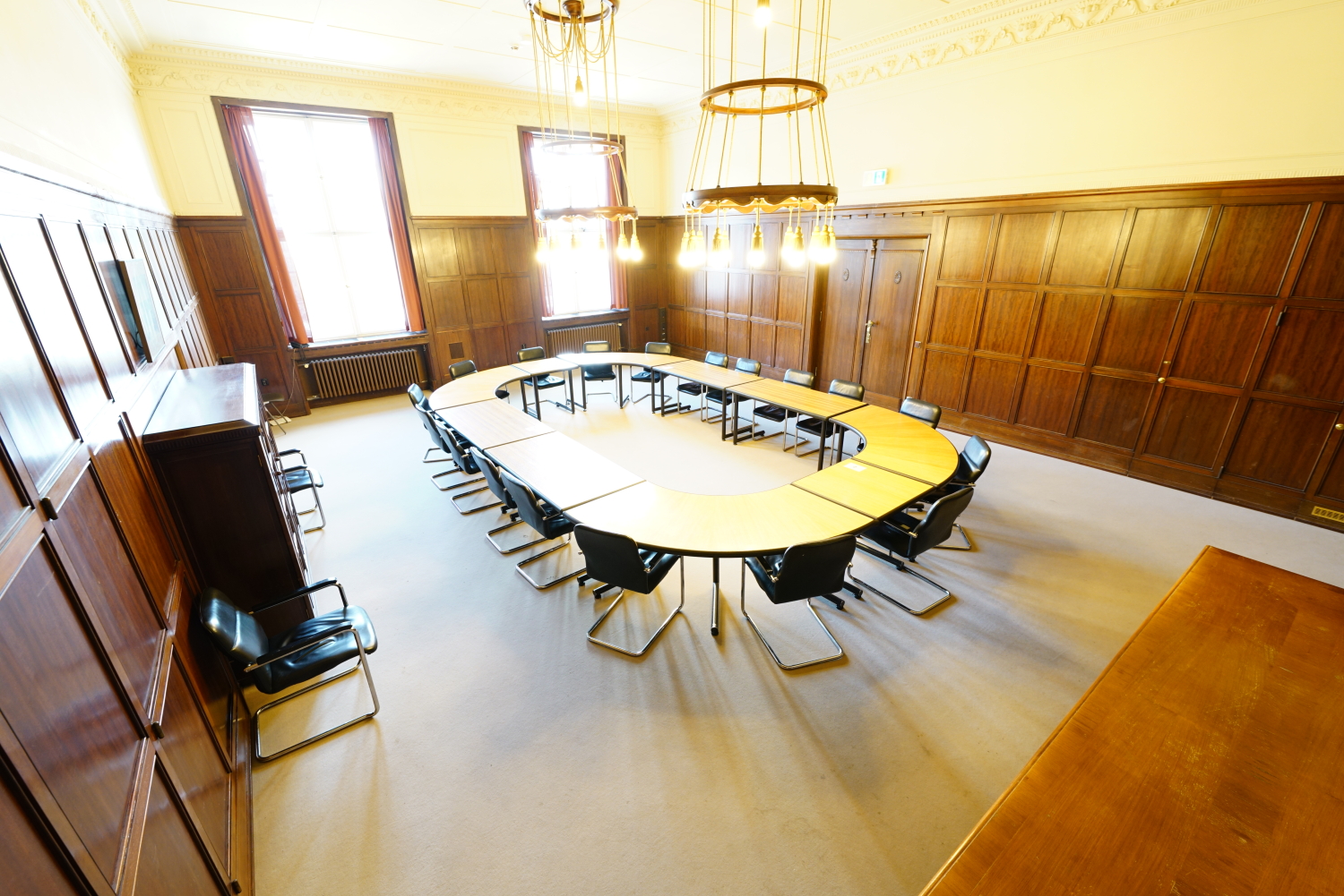 Saalit mit rundem O-Tisch und holzverkleideten Wänden