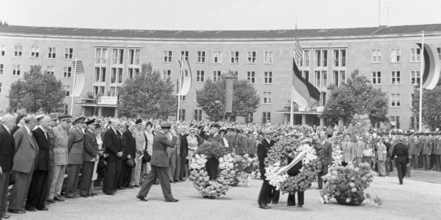 mehrere Personen in Uniformen halten Kränze in den Händen