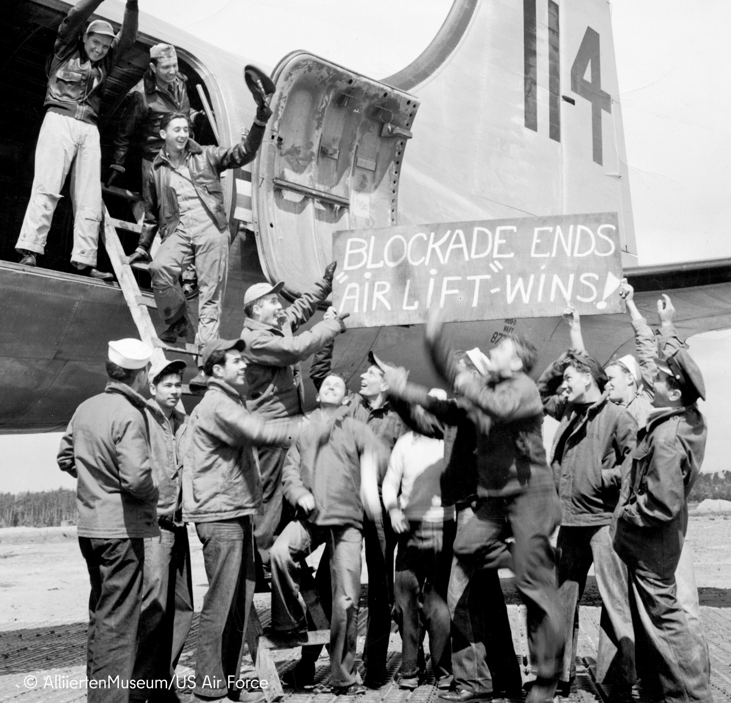 Viele Männer halten ein Schild hoch mit der Aufschrift "Blockade ends air lift wins!"