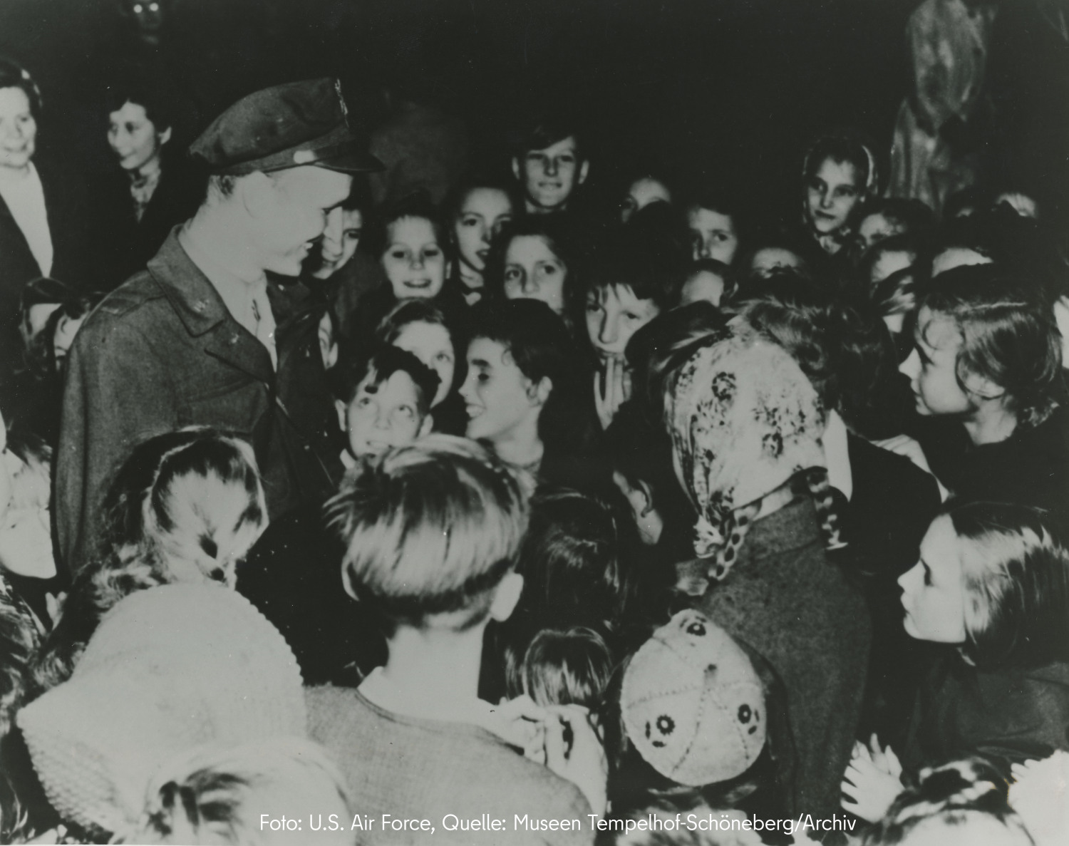 A man in uniform stands in a crowd of children