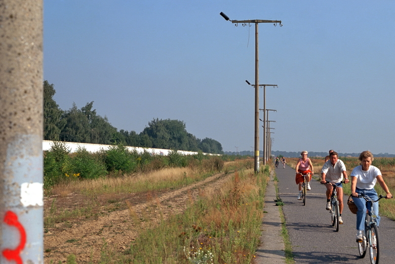 Menschen auf Fahrrädern fahren an einer Reihe von Straßenlaternen entlang
