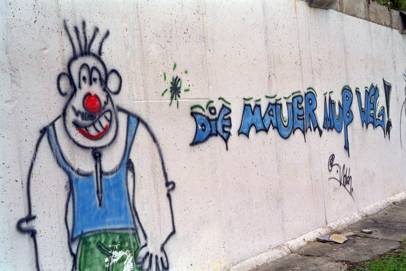 eine besprühte Betonwand mit der Aufschrift "Die Mauer muss weg!"