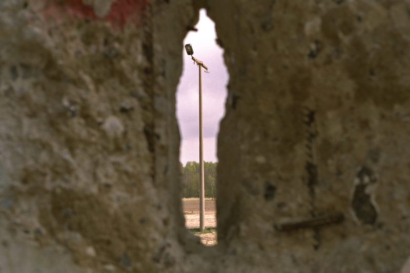 eine Straßenlaterne durch einen Spalt in einer Betonwand