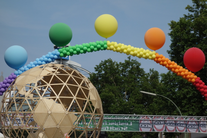 Weltkugel mit Ballons in Regenbogenfarben im Hintergrund
