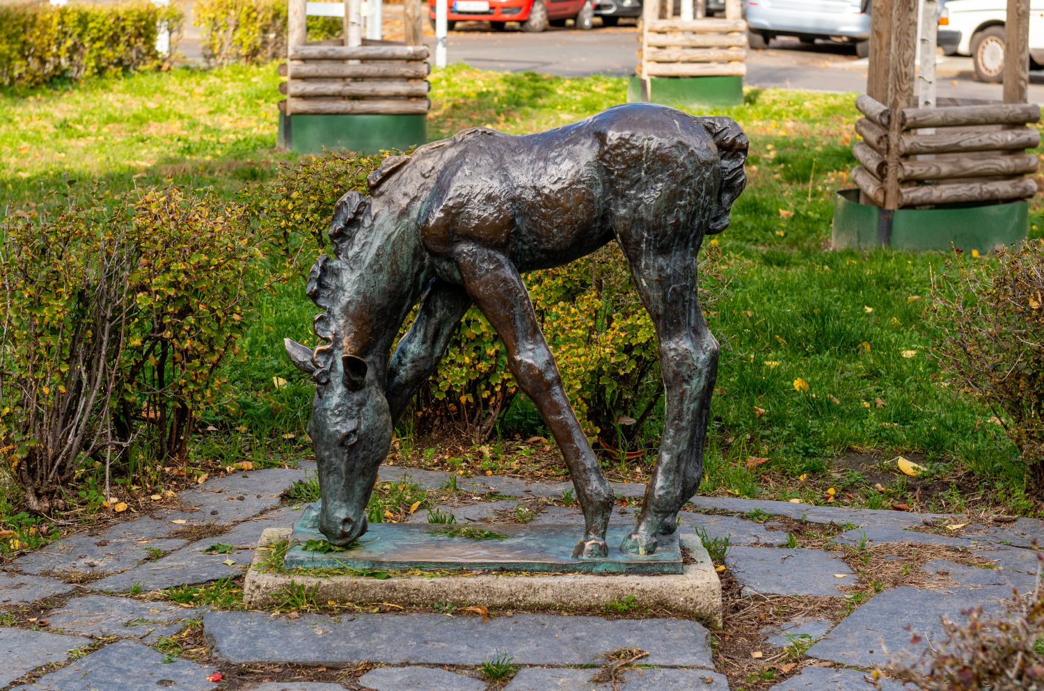 Skulptur eines grasenden Fohlens vor einer Grünfläche.