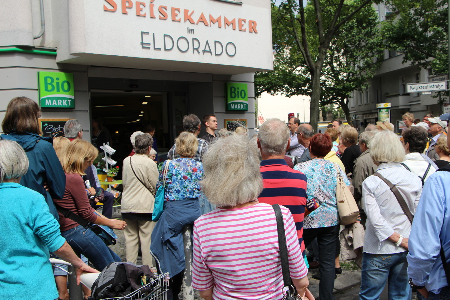 Menschen stehen vor einem Bio-Markt mit der Aufschrift Speisekammer im Eldorado