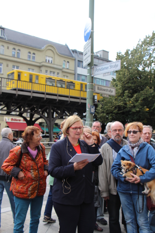 Frau spricht vor Mesnschen vor der Hochbahn