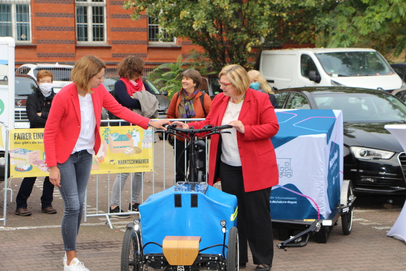 Zwei Frauen besichtigen ein Lastenfahrrad. 