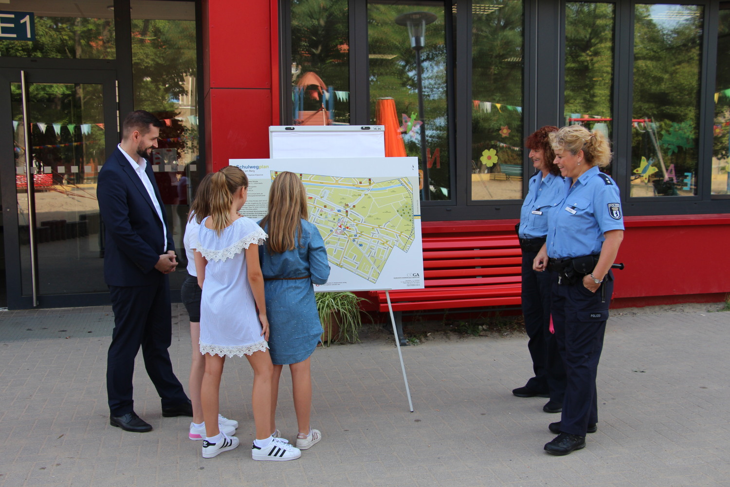 Verkehrssicherheitsberaterinnen der Berliner Polizei und Schülerinnen der Schule am Berg zeigen Marco Brauchmann ihre sicheren Schulwege auf dem neuen Plan.