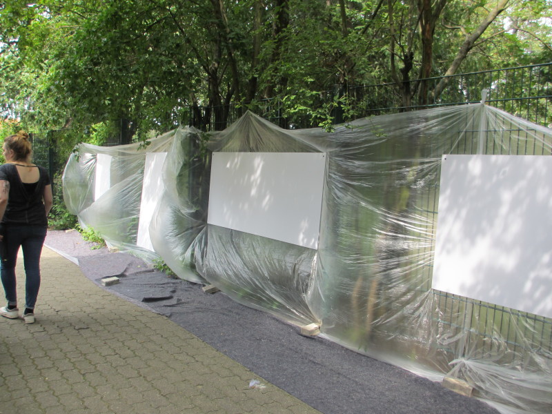 Zaun und Pflanzen werden mit einer Plastikplane vor dem Einsatz der Spraydosen geschützt