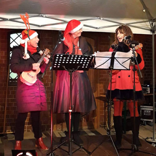 drei Frauen mit Ukulelen und Weihnachtsmützen
