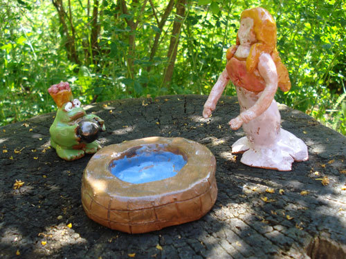 eine aus Keramik geformte Figurengruppe mit einer weiblichen Figur einem Frosch aneinem Brunnen
