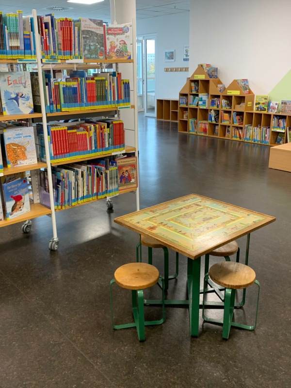 Tisch, Stühle und Regale in der Kinderabteilung