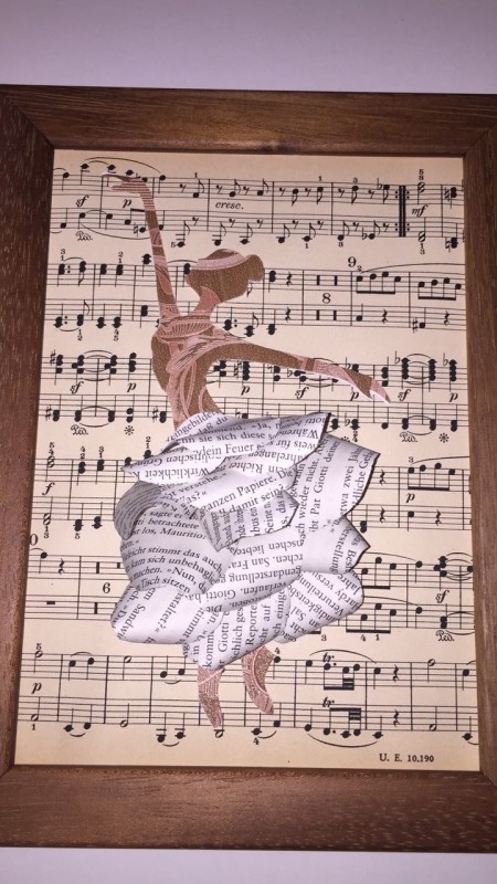 Tänzerin aus Buchseiten gebastelt vor Hintergrund aus Notenpapier
